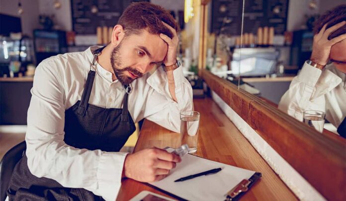 tired-male-barista-with-pills-sitting-at-wooden